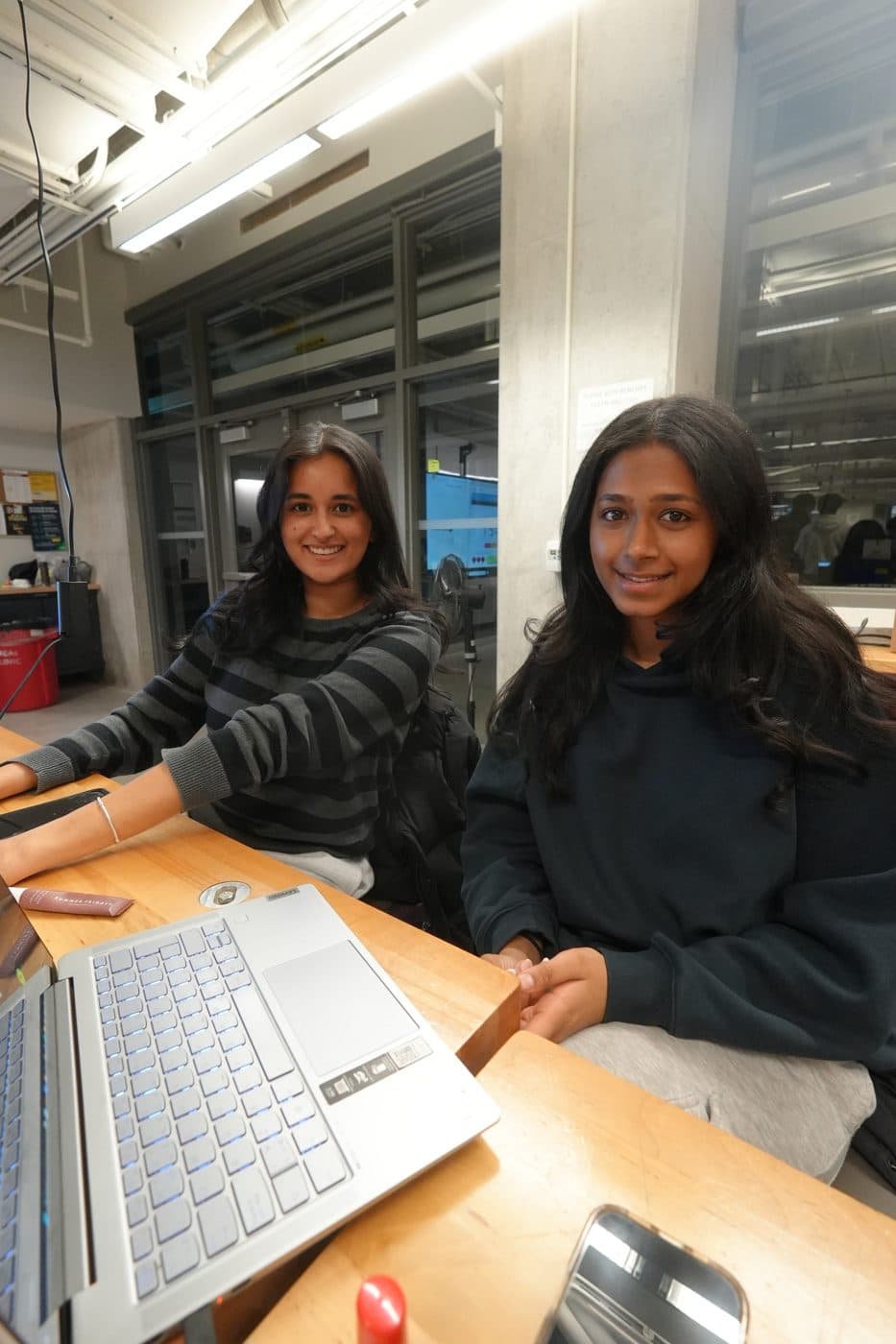 Two builders smiling at their laptops